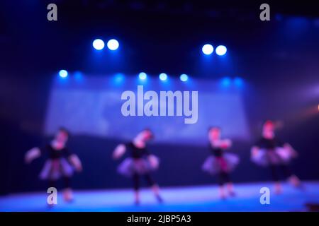 Ein verschwommener abstrakter Hintergrund eines Tanzfestivals von einer Gruppe von Mädchen in der Anzahl von vier Personen. Helle Beleuchtung der blauen Tanzfläche. Hochwertige Fotos Stockfoto