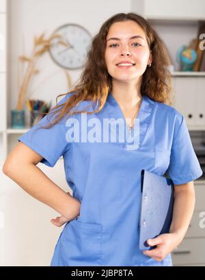 Positive Ärztin in blauem Hemd im medizinischen Zentrum stehend Stockfoto