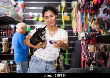 Asiatische Frau mit Hund Auswahl Kragen im Tiergeschäft Stockfoto