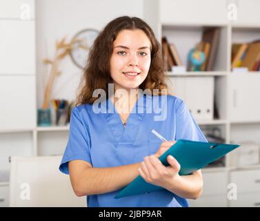 Positive Ärztin in blauem Hemd im medizinischen Zentrum stehend Stockfoto