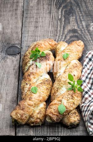 Blätterteiggeflecht, gefüllt mit Hackfleisch auf einem Holztisch Stockfoto