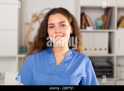 Positive Ärztin in blauem Hemd im medizinischen Zentrum stehend Stockfoto
