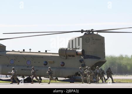 Soldaten verlassen einen CH-47 Chinook Hubschrauber während einer Luftangriffsmission, um die 11. Airborne Division Aktivierungszeremonie am 6. Juni 2022 im Ladd Army Airfield auf Fort Wainwright, Alaska, zu starten. Soldaten des Stryker Brigade Combat Teams 1. tauschten ihre 25. Patches der Infanterie-Division gegen die der historischen Airborne Division 11. ein und werden in Alaska als 1. Brigade Combat Team der „Arctic Angels“ dienen, das sich auf Einsätze bei extremer Kälte und in gebirgigen Höhenlagen spezialisiert hat. (Foto der Armee/John Pennell) Stockfoto