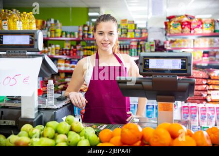 Porträt eines lächelnden Verkäufermädchen, das hinter der Theke mit Schuppen steht Stockfoto