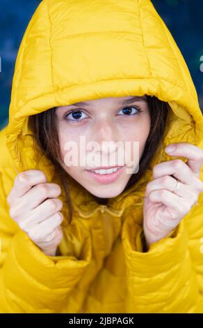 Frau, die die Kamera mit gelber Kapuze anschaut Stockfoto