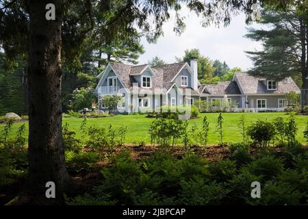 Neues Haus im Hampton Cottage-Stil, eingerahmt von Sträuchern und Pinus - Pinien im Frühling, Quebec, Kanada. Dieses Bild ist Eigentum freigegeben. CUPR0208 Stockfoto