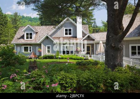 Neues Haus im Hampton Cottage-Stil und rosarot Dicentra spectabilis - blutende Herzblumen im Frühling an der Grenze. Stockfoto