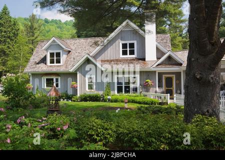 Neues Haus im Hampton Cottage-Stil und rosarot Dicentra spectabilis - blutende Herzblumen im Frühling an der Grenze. Stockfoto