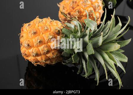 Kleine Ananas auf schwarzem Tisch, Nahaufnahme Stockfoto