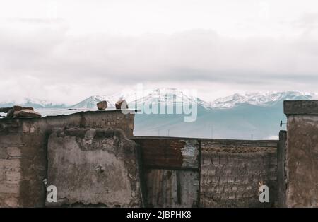 Schöne trockene Landschaft mit rustikalen Bau, schneebedeckten Bergen und bewölktem Himmel in Salinas und Aguada Blanca National Reserve, peruanischen Altiplano ne Stockfoto