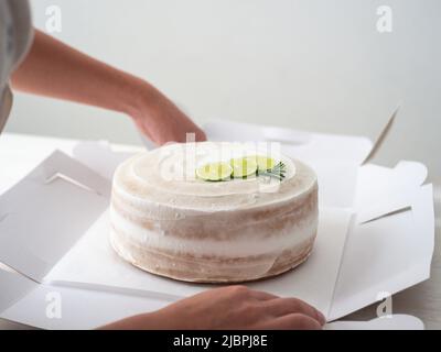 Vegane Geburtstagstorte mit Mandel, Kokosnuss und Zitronenbasis in einer weißen Schachtel Stockfoto