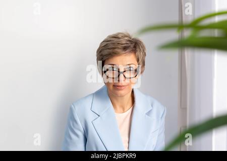 Porträt einer Geschäftsfrau in blauem Anzug, Brille. Stockfoto