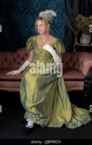 Eine Regency-Frau in einem grün gedrehten Seidenkleid und sitzt in ihrem Salon Stockfoto