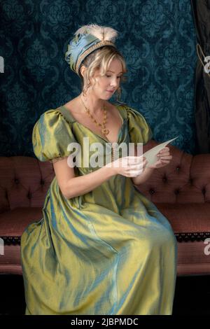 Eine Regency-Frau in einem grün gedrehten Seidenkleid und sitzt in ihrem Salon Stockfoto