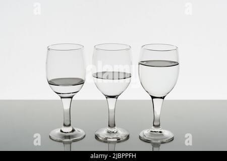 Drei mit Wasser gefüllte Weingläser spiegeln sich auf dem Tisch wider Stockfoto