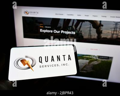 Person, die das Smartphone mit dem Logo des US-Infrastrukturunternehmens Quanta Services Inc. Auf dem Bildschirm vor der Website hält. Konzentrieren Sie sich auf die Telefonanzeige. Stockfoto