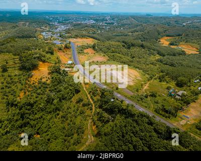 Luftaufnahme der National Route 14 in der Provinz Binh Phuoc, Vietnam mit hügeliger Landschaft und spärlicher Bevölkerung rund um die Straßen. Reise- und Landschaftsverh Stockfoto