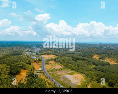 Luftaufnahme der National Route 14 in der Provinz Binh Phuoc, Vietnam mit hügeliger Landschaft und spärlicher Bevölkerung rund um die Straßen. Reise- und Landschaftsverh Stockfoto