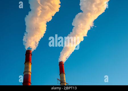 Weißer Rauch kommt aus den Rohren am blauen Himmel Stockfoto