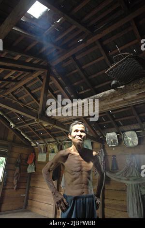 Porträt von Daniel Rajang, ehemaliger Tumenggung (traditioneller Häuptling) der Gemeinde Orung da'an Dayak, in seiner Bauernhütte im Dorf Nanga Raun, Kalis, Kapuas Hulu, West Kalimantan, Indonesien. Die Orung da'an-Gemeinde besaß einst das längste Langhaus in Kalimantan, aber es verschwand nach einem Feuerunfall vor ein paar Jahrzehnten, sagte er. Stockfoto