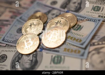 Bitcoin-Münze auf 100-Dollar-Banknoten aus den vereinigten Staaten von amerika. Digitale Krypto-Währung und US-Dollar-Währung. Gold glänzende Münzen auf Haufen Stockfoto