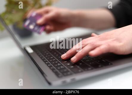 Das Foto vom 30/03/20 einer Frau, die einen Laptop benutzt, während sie eine Bankkarte in ihrem Besitz hat, da mehr als zwei von fünf kürzlich gekauften Kunden jetzt später bezahlen (BNPL) und sich schließlich Geld leihen mussten, um ihre Rückzahlungen zu tätigen, so der Rat der Bürger. Stockfoto