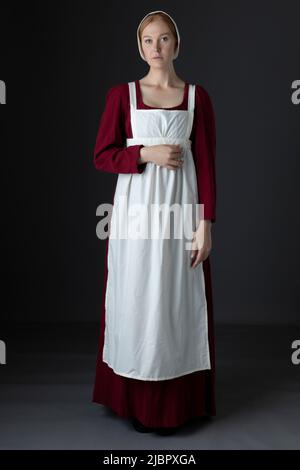 Ein Regency Dienstmädchen, das ein rotes Kleid und eine Schürze trägt Stockfoto