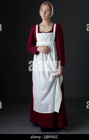 Ein Regency Dienstmädchen, das ein rotes Kleid und eine Schürze trägt Stockfoto