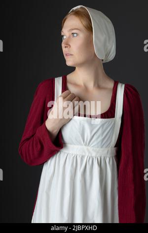 Ein Regency Dienstmädchen, das ein rotes Kleid und eine Schürze trägt Stockfoto