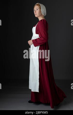 Ein Regency Dienstmädchen, das ein rotes Kleid und eine Schürze trägt Stockfoto