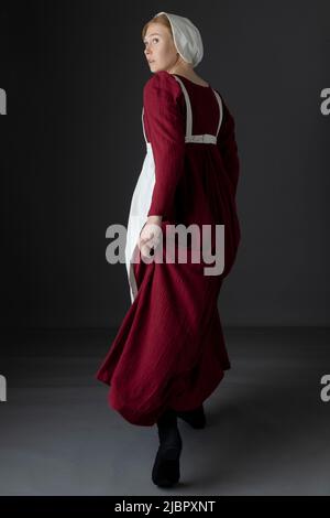 Ein Regency Dienstmädchen, das ein rotes Kleid und eine Schürze trägt Stockfoto