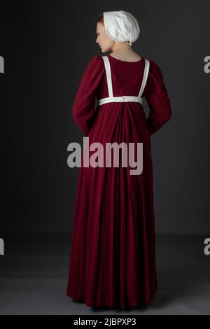 Ein Regency Dienstmädchen, das ein rotes Kleid und eine Schürze trägt Stockfoto