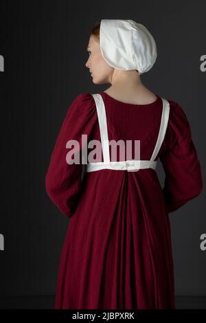 Ein Regency Dienstmädchen, das ein rotes Kleid und eine Schürze trägt Stockfoto