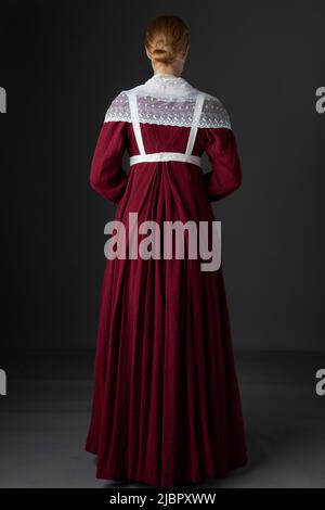 Ein Regency Dienstmädchen, das ein rotes Kleid und eine Schürze trägt Stockfoto