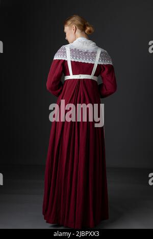 Ein Regency Dienstmädchen, das ein rotes Kleid und eine Schürze trägt Stockfoto