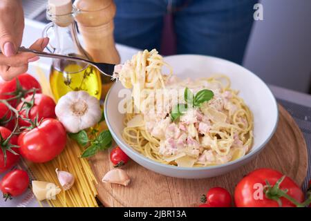 Hausgemachte Pasta Carbonara mit frischem Basilikum und Parmesan in Keramikschale Stockfoto