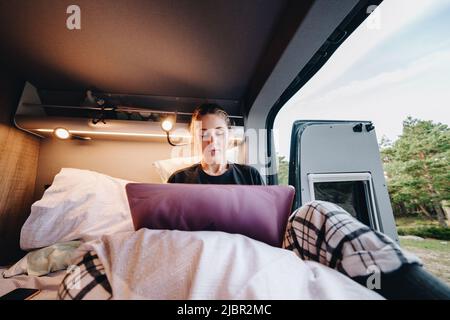 Junge Frau mit Laptop im Wohnmobil Stockfoto