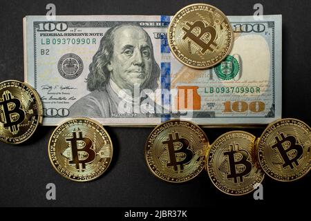 Gold Bitcoin Münzen auf hundert Dollar Banknoten. BTC-Umschreibung in USD. Währung der Vereinigten Staaten von Amerika. Stockfoto