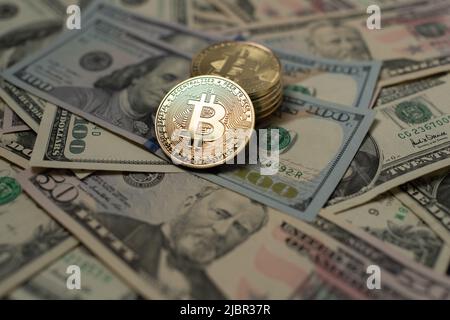 Bitcoin auf 100-Dollar-Banknoten. Die BTC stapelten sich auf und verteilten Dollarscheine. Der Handel mit Kryptowährung und US-Dollar. Stockfoto