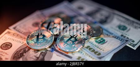 Goldbitcoins auf Hundert-Dollar-Banknoten aus den USA. Vereinigte Staaten von Amerika Währung mit Kryptowährung Bitcoin. Beleuchtet von Orange und White Lig Stockfoto