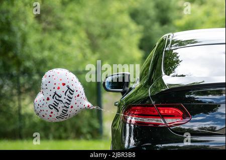 Rottweil, Deutschland. 04.. Juni 2022. Vor der Kirche ist ein Ballon in Herzform mit der Inschrift Just Married an einem Brautwagen befestigt. Kredit: Silas Stein/dpa/Alamy Live Nachrichten Stockfoto