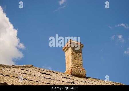 Ein alter Ziegelkamin an einem blauen Himmel. Stockfoto