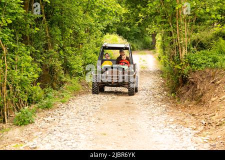 Jungs fahren in einem John Deere Gator Utility Vehicle, High Bickington, Devon, England, Vereinigtes Königreich. Stockfoto