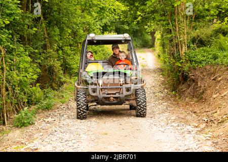 Jungs fahren in einem John Deere Gator Utility Vehicle, High Bickington, Devon, England, Vereinigtes Königreich. Stockfoto