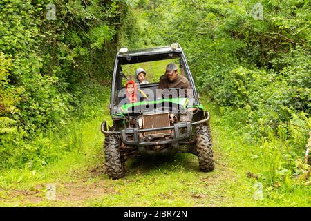 Jungs fahren in einem John Deere Gator Utility Vehicle, High Bickington, Devon, England, Vereinigtes Königreich. Stockfoto