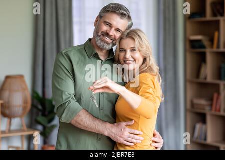 Ein glückliches Paar mittleren Alters, das die Schlüssel hielt und lächelte Stockfoto