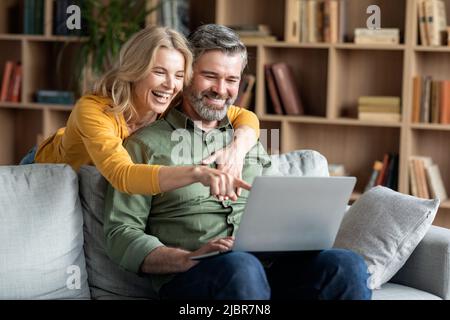 Fröhliche Ehegatten Mittleren Alters Mit Laptop Spaß Und Entspannung Zu Hause Stockfoto