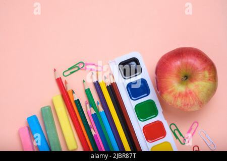 Apfel, Schulbedarf und Papeterie rosa Hintergrund. Stockfoto