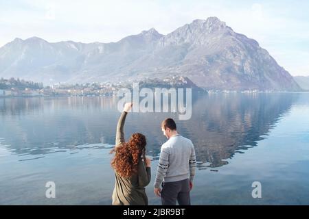 Weiches, rückeres Paar, das romantische Dates am Ufer des Lake Lecco, Italien, genießt. Menschen in der Liebe auf dem Hintergrund der Berge, Wasser im Freien. Romantische Beziehungen, Abenteuer, Urlaub. Speicherplatz kopieren Stockfoto