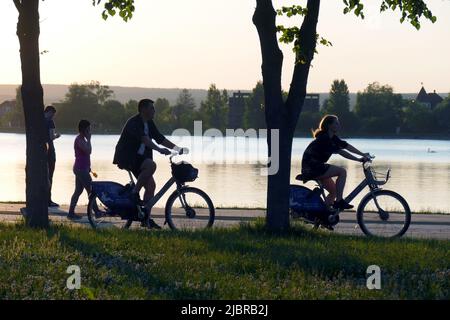 IVANO-FRANKIVSK, UKRAINE - 07. JUNI 2022 - am Abend fahren die Menschen mit dem Fahrrad entlang des Kais des Stadtsees, Ivano-Frankivsk, Westukraine. Dieses Foto kann nicht in der russischen Föderation verteilt werden. Stockfoto